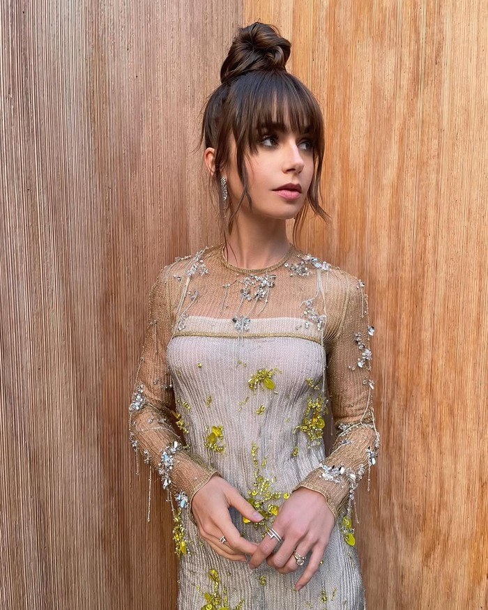 Gaya bun Lily Collins berpadu sempurna dengan face-framing bangs. Tampilan ini memberi kesan elegan dan klasik./ Foto: instagram.com/gregoryrussellhair