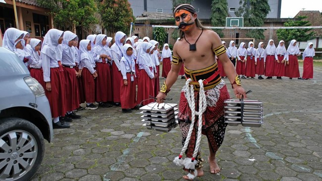 Relawan Satuan Pelayanan Pemenuhan Gizi (SPPG) Danupayan berpakaian seni Warokan saat mendistribusikan makan bergizi gratis (MBG) ke SD Negeri Pandemulyo di Bulu, Temanggung, Jawa Tengah, Senin (19/1/2026). Kegiatan relawan SPPG berpakaian Warokan da