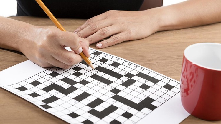 Adult woman solving crossword puzzle with yellow pencil&period;