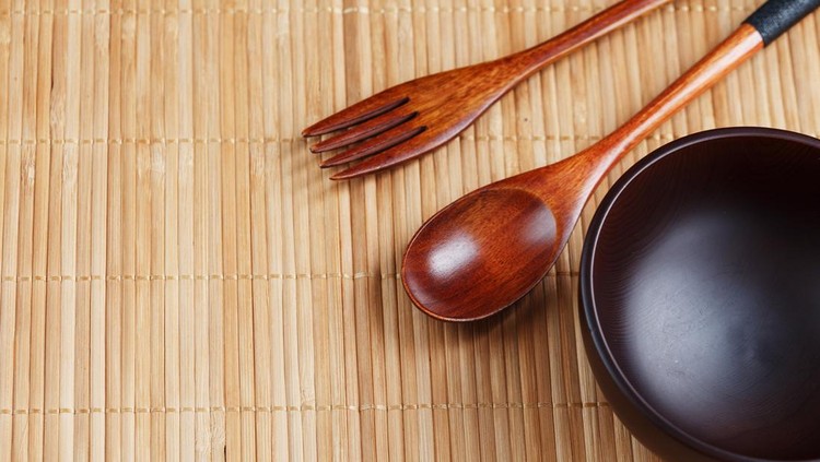 Natural wood plate&comma; spoon and fork on a bamboo backing&period; Asian food handicraft concept&period; View from above
