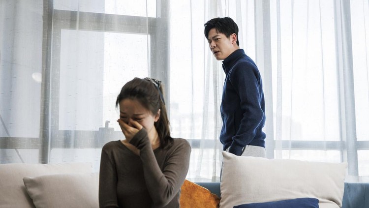 This is a young asian couple&period; They wear casual clothes&period; Sitting on the sofa in the living room at home&period; There was a quarrel between them&comma; and the man was very excited&period; Women are sad&period;