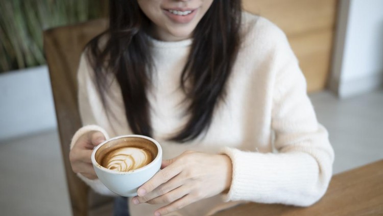Smiling woman in sweater holding cup of coffee&period;