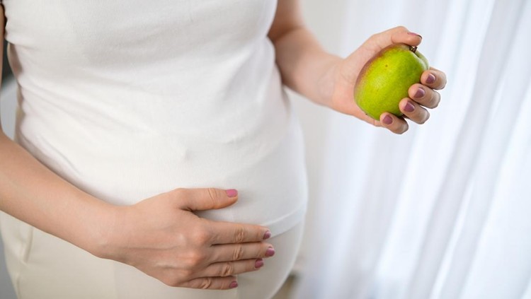Close up pear in pregnant womans hand&period; Diet&comma; fruits and vitamins during pregnancy