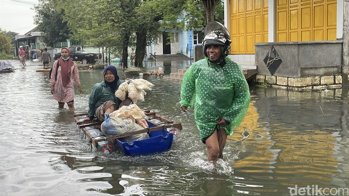 Warga Desa Mintomulyo, Pati, naik rakit gegara desanya tergenang banjir selama dua pekan ini.