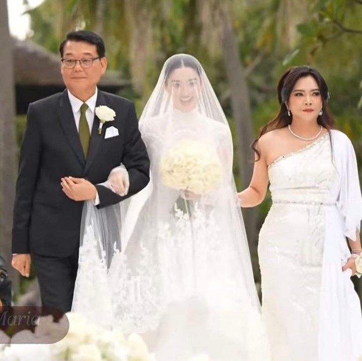 <p>Ranty Maria dan Rayn Wijaya menggelar pemberkatan nikah mereka di Nusa Dua, Bali. Sebelum prosesi pemberkatan dimulai, Ranty terlihat digandeng oleh sang Ayah, Lee Ki Young, yang berasal dari Korea saat berjalan menuju altar pernikahan. Di samping kiri Ranty juga ada sang Bunda. Senyum sumringah pun terlihat jelas di wajah Ranty di hari bahagianya itu. (Foto: Youtube @TSMediaID)</p>