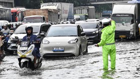 Petugas Kepolisian (kanan) mengatur lalu lintas kendaraan yang terjebak kemacetan saat melintasi genangan air di Cawang, Jakarta, Rabu (4/2/2026). Curah hujan tinggi dan buruknya perawatan drainase menyebabkan genangan air merendam jalan DI Panjaitan