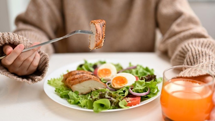 Cropped image&comma; Diet woman eating a fresh healthy salad with grilled chicken breast or chicken fillet and orange juice at the dining table&period;