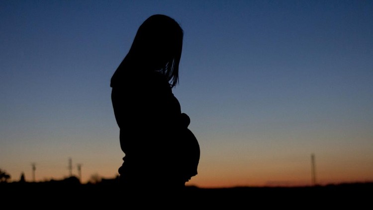 A pregnant woman is silhouetted against a colorful sunset in Toledo&comma; CM&comma; Spain