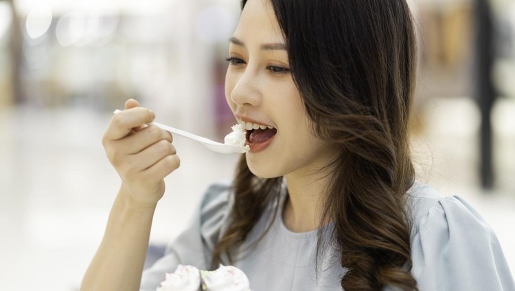 Young girl sitting alone eating cream cake at the mall