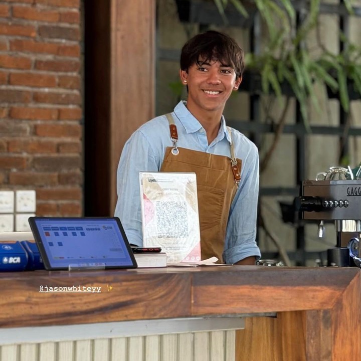 <p>Melalui unggahan di Instagram, Nana memamerkan kesibukan putranya saat magang. Dalam satu potret yang dibagikan, Jason terlihat berdiri di depan mesin pembuat kopi sambil mengenakan apron berwarna cokelat. (Foto: Instagram @nanamirdad_)</p>