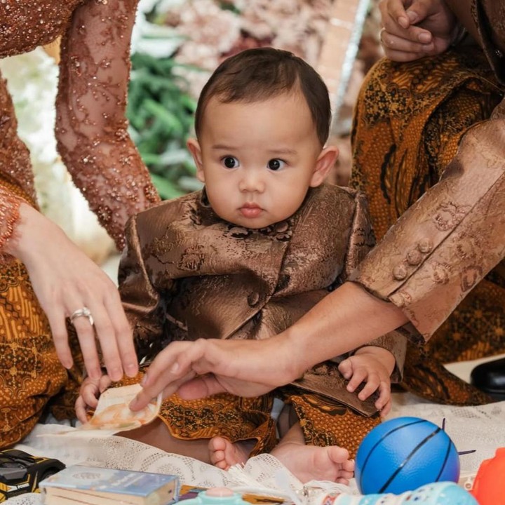 <p><em>Baby </em>Arash tampil begitu menggemaskan dengan beskap berwarna cokelat, Bunda. Penampilannya semakin menarik perhatian karena dipadukan dengan kain batik tradisional sebagai bawahan. (Foto: Instagram @aaliyah.massaid/@thariqhalilintar)</p>