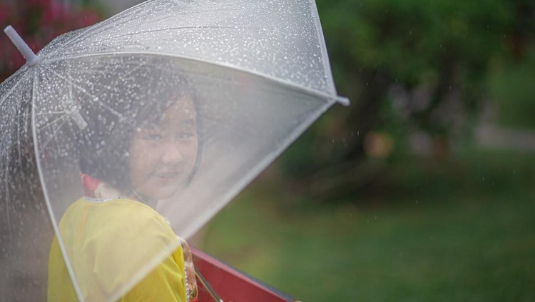 Asia Chinese girl holding umbrella and moon cake box walking in public park rainy day&period; She enjoying mid-autumn festival&period;