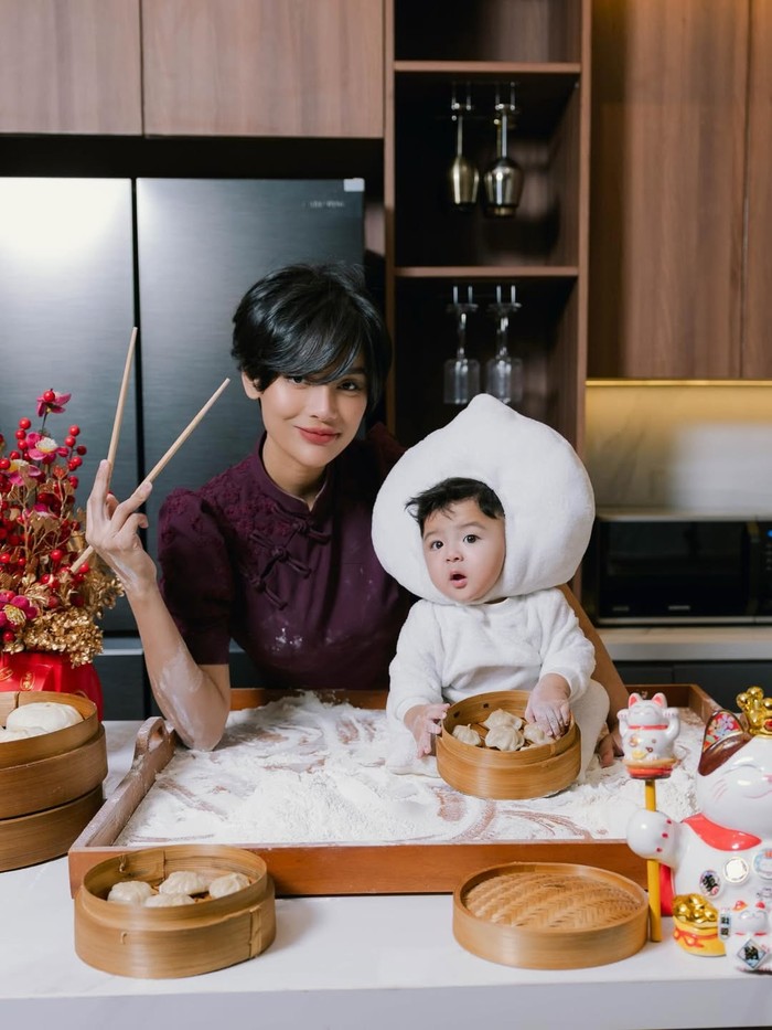 Maroon yang jadi primadona pada Tahun Baru Imlek kali ini juga dipakai oleh Erika Carlina saat photoshoot, Beauties.&nbsp;Qipao&nbsp;berdetail puff sleeves&nbsp;serta bordiran di pundak dipakainya. Sementara Andrew tampak menggemaskan dalam kostum bao/ Foto: instagram.com/eri.carl