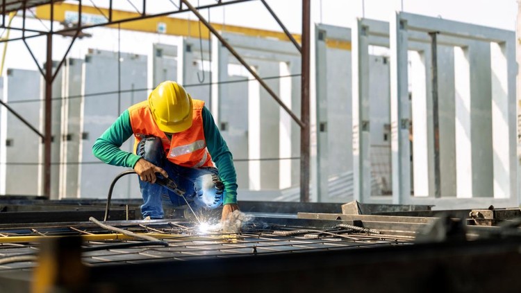 Workers at a construction site weld metal structures of precast concrete slabs&period;