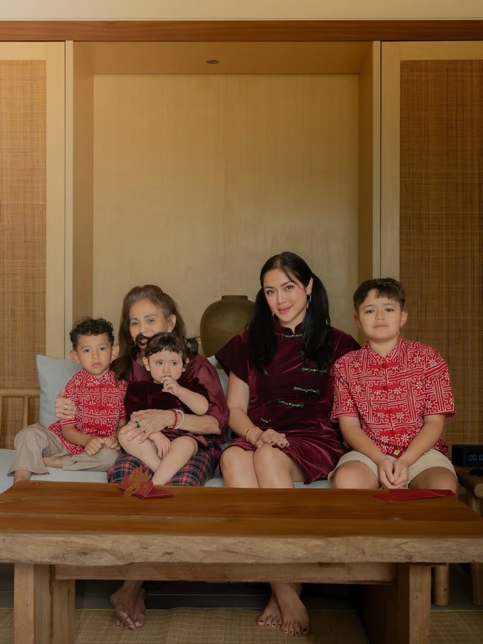 Qiapo velvet rona maroon dengan kancing pankou kontras warna hijau dikenakan Jessica Iskandar.&nbsp;Outfit&nbsp;rancangan Cynthia Tan itu serasi dengan gaun yang dikenakan Hagia. / Foto: instagram.com/inijedar