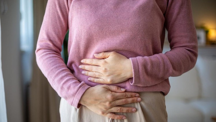 Mid adult woman holding her belly suffering from abdominal pain