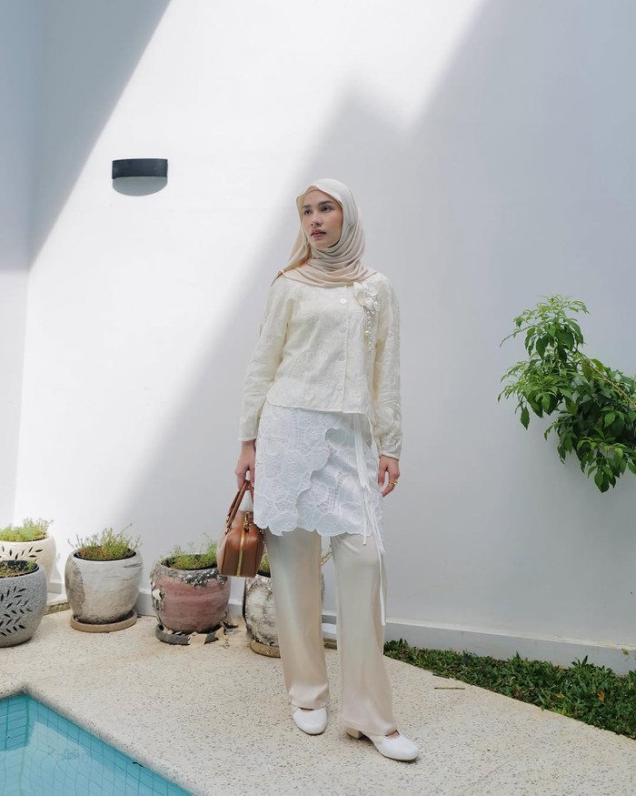 Kamu bisa tampil elegan saat ke kantor dan bukber dengan meniru gaya Dwi Handayani yang mengenakan blus bordir dan rok yang dibuat seolah tunik dengan detail layer./ Foto: Instagram.com/dwihandaanda