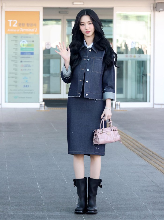 Karina aespa mengenakan setelan denim yang stylish. Jaket berlapis kemeja dipadukan dengan rok span selutut serta knee-length boots. Sementara tas Prada Bonnie rona pink mengaksentuasi gaya/ Foto: Dok. Prada