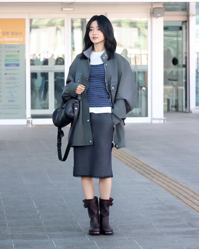 Taeri Kim menampilkan gaya layering dengan tanktop, kaus putih, dan jaket sebagai airport style musim dingin, Beauties. Layering atasan itu dikenakan bersama pencil skirt abu-abu polos dengan tepian renda yang membuat gayanya tampak&nbsp;understated./ Foto: Dok. Prada