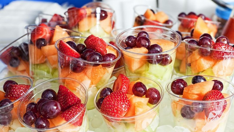 Strawberries&comma; red grapes&comma; cantaloupe offered in plastic cups on ice at a food fair&period;