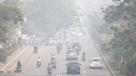 Sejumlah pengendara motor melintasi jalan yang diselimuti kabut asap dari kebakaran hutan dan lahan (karhutla) di Kalbar.