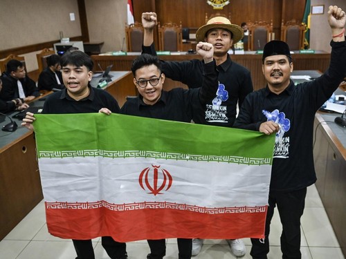 Terdakwa kasus dugaan penghasutan unjuk rasa, Delpedro Marhaen (kedua kiri), Muzaffar Salim (kiri), Syahdan Husein (kanan) dan Khariq Anhar (kedua kanan) membawa bendera Iran sebelum menjalani sidang putusan di Pengadilan Tipikor, Jakarta, Senin (19/