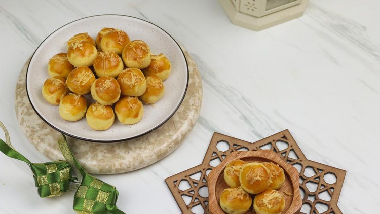 Nastar cookies&comma; typical of hari raya cookies filled with pineapple jam and garnish with grated cheese&period; Eid Mubarak concept background with ketupat and Islamic decoration&period;