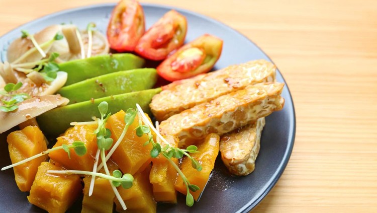 Plate of Pan fried Tempeh and Colorful Vegetables Salad Garnished with Daikon Sprouts