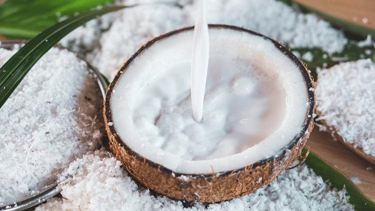 pouring fresh coconut milk and coconut fruit ingredient on wooden table