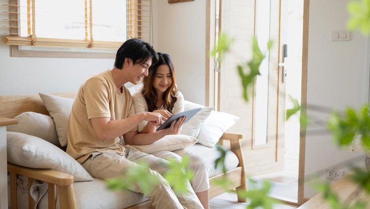 Relaxed asian couple using a digital tablet while relaxing together on sofa at home&period;&period;
