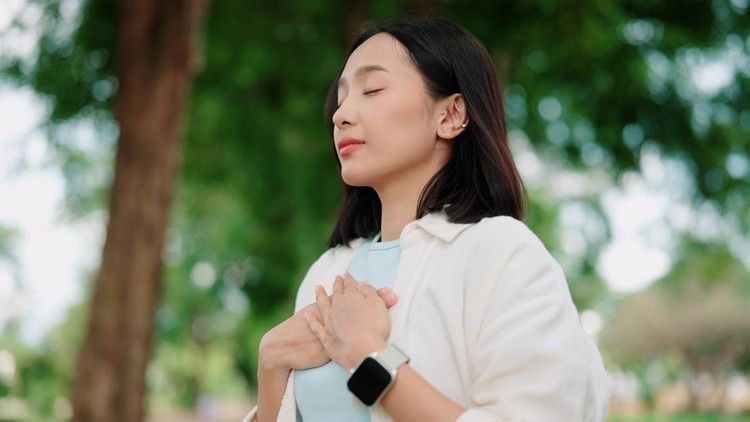 Asian woman focusing on breathing exercise in the park&period;