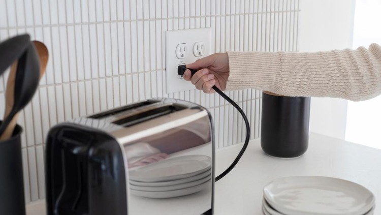 Plugging in a toaster into an electrical outlet
