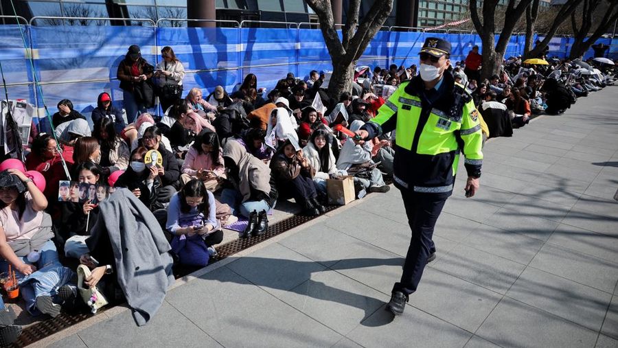 Para penggemar grup Kpop BTS bersorak menjelang konser 'BTS The Comeback Live Arirang' saat mereka menunggu di dekat lokasi konser, di pusat kota Seoul, Korea Selatan, 21 Maret 2026. (REUTERS/Kim Hong-ji)