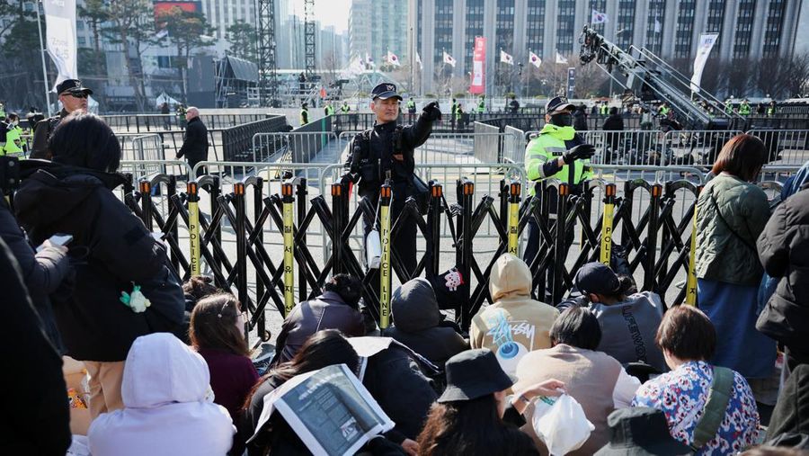 Para penggemar grup Kpop BTS bersorak menjelang konser 'BTS The Comeback Live Arirang' saat mereka menunggu di dekat lokasi konser, di pusat kota Seoul, Korea Selatan, 21 Maret 2026. (REUTERS/Kim Hong-ji)