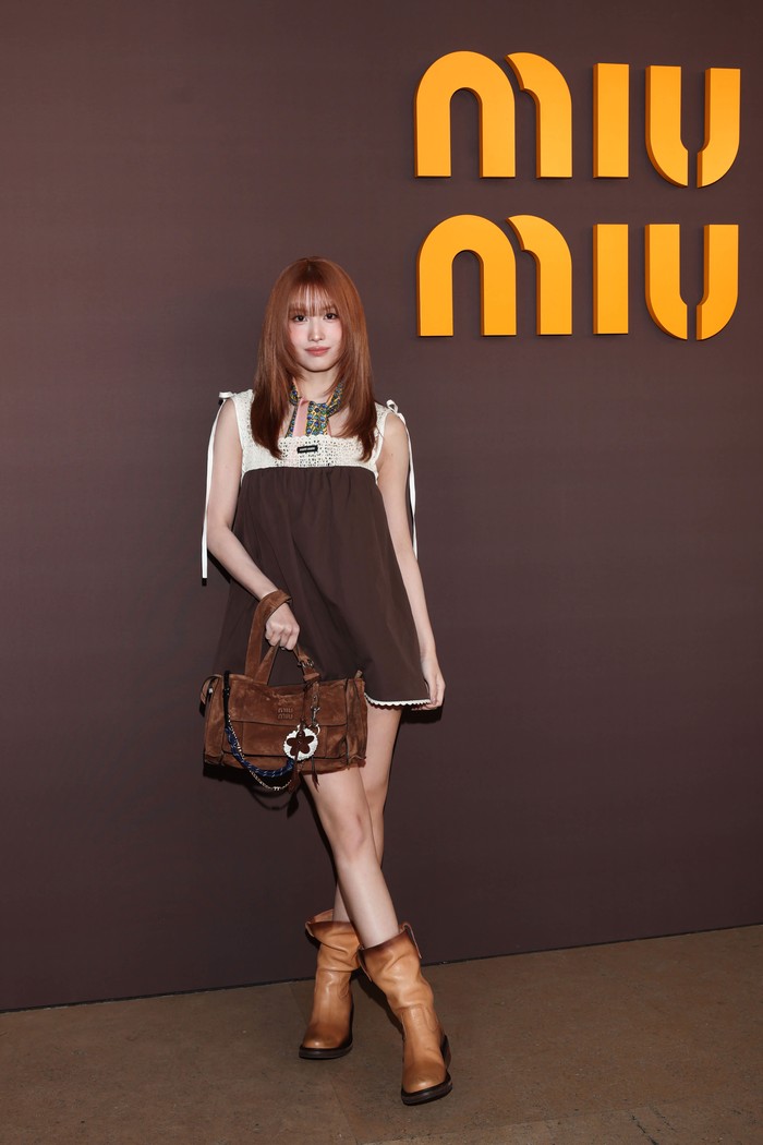 Momo TWICE tampil manis dalam mini dress coklat&nbsp;dengan panel renda yang dipadukan scarf serta boots. Dalam palet warna senada, tekstur dan siluet membuat gayanya menarik/ Foto: Dok. Miu Miu