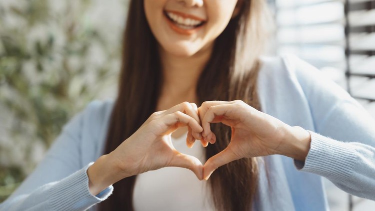 Focus on young woman's hands making heart sign with her hands