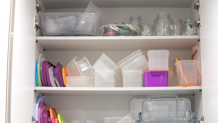 Open kitchen cupboard full of plastic and glass containers inside&period;