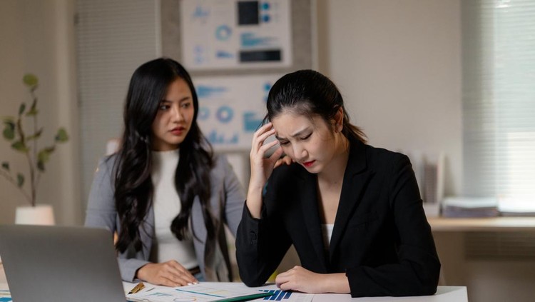 Professional women analyzing financial data&comma; experiencing stress-related headache in corporate workspace