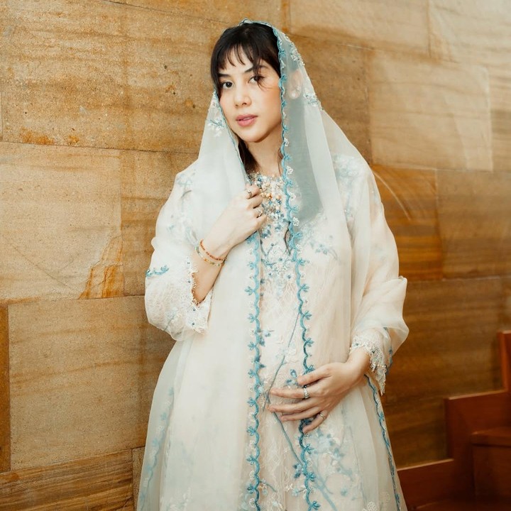 <p>Dalam acara tasyakuran ini, Dinda tampil cantik mengenakan baju muslim berwarna putih, berhias aksen bordir bunga warna biru muda yang dipadukan dengan pasmina senada. Dalam balutan pakaian ini, Dinda memamerkan <em>baby bump</em> kehamilannya yang sudah terlihat jelas. (Foto: Instagram @adindathomas)</p>