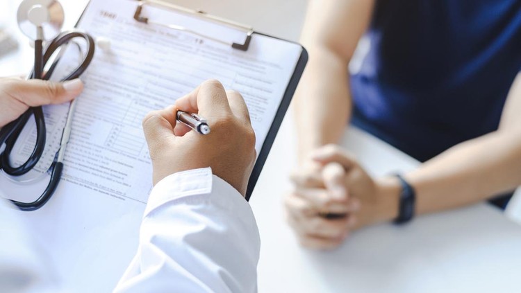 Close-up of a male doctor hand hold a silver pen and showing pad in hospital&period; Doctor giving prescription to the patient and filling up medical form at a clipboard
