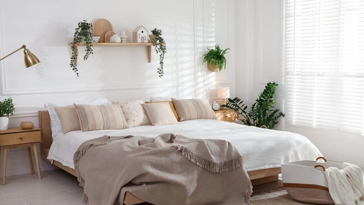 Stylish bedroom interior with large bed&comma; houseplants and decorative elements
