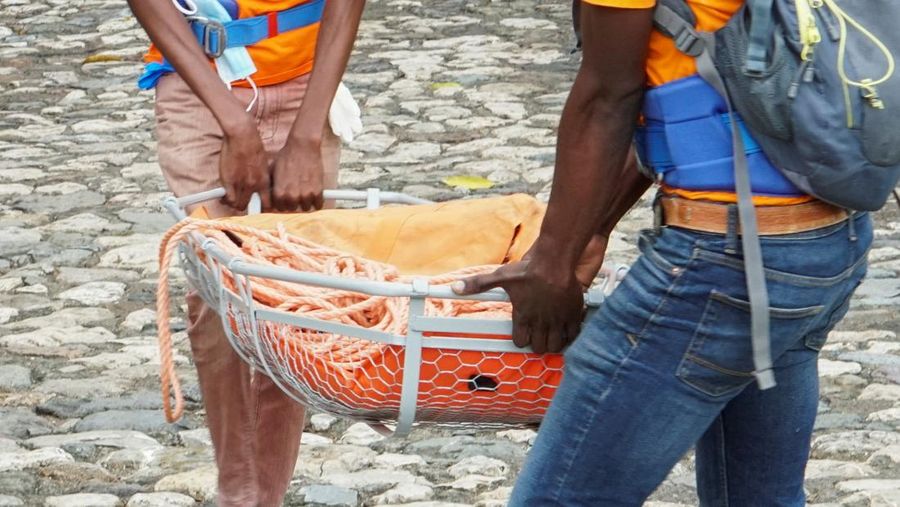 Orang-orang membantu membikin tandu untuk mengangkut jenazah korban setelah Departemen Perlindungan Sipil Haiti untuk wilayah Utara mengatakan bahwa kejadian saling sorong menewaskan beberapa orang di Benteng Laferriere, sebuah tembok awal abad ke-19 nan dipenuhi oleh siswa dan visitor untuk seremoni tahunan situs Warisan Dunia UNESCO, di Milot, Haiti, 12 April 2026. (REUTERS/Richardson Ulysse)