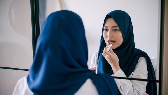 ilustrasi org berjilbab pakai lipbalm