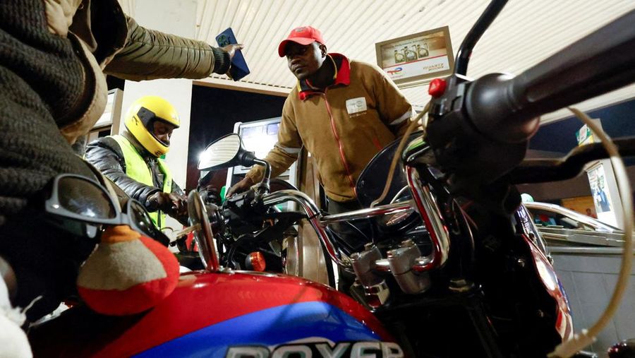 A fuel pump attendant confirms a mobile phone payment as he fuels a motorcycle taxi at a TotalEnergies petrol station ahead of an announced fuel price hike, as fuel costs rise amid dunia disruptions caused by the Iran war, in Nairobi, Kenya April 14, 2026. REUTERS/Thomas Mukoya
