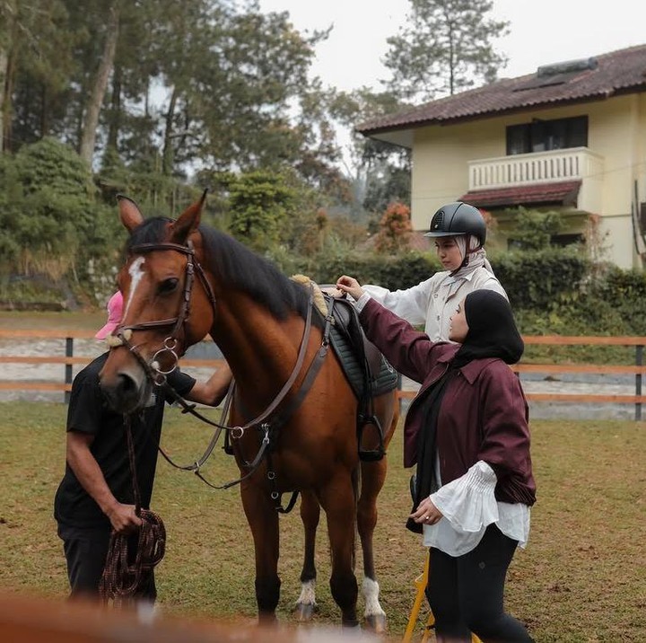 <p>Pada momen yang sama, Tya Ariestya terlihat penasaran dan ikut mencoba suasana berkuda di lingkungan yang sejuk. Dalam foto tersebut, Zaskia pun tampak membantu Tya untuk naik ke atas kuda. (Foto: Instagram @zaskiasungkar15)</p>