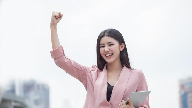 Successful asian business woman arms up celebrating with tablet computer in hand in city outdoors &period; girl excited winner&period;Cheerful &comma;happy&comma; female checking online good news