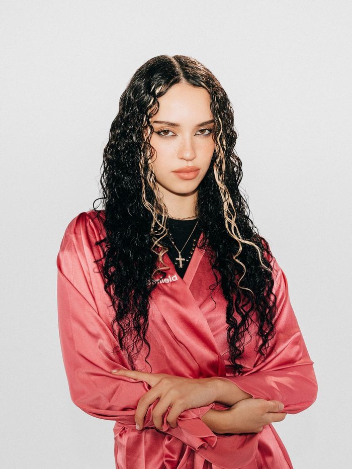 Rambut keriting panjang KATSEYE Daniela semakin on-point dengan tatanan ala mermaid. Dark gloss dipadu highlight tipis yang membingkai wajah membuat visualnya semakin memancar. Hair stylist menonjolkan rambut keritingnya dengan memberikan hidrasi intens serta kilau wet-look lewat Matrix Food For Soft Oil Serum, Beauties./ Foto: Dok. Matrix