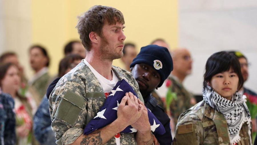 Seorang veteran dari golongan About Face memegang bendera pemakaman simbolis untuk menghormati orang meninggal saat polisi menangkapnya selama protes menentang perang Iran, di Rotunda Gedung Kantor Cannon House di Capitol Hill di Washington, D.C., AS, 20 April 2026.