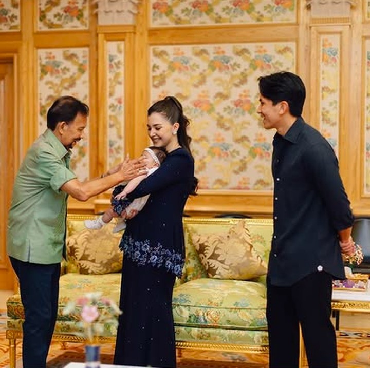 <p>Dalam potret yang dibagikan di Instagram Stories, Pangeran Mateen mengunggah suasana hangat pertemuan sang putri dengan kakeknya Hassanal Bolkiah, yang merupakan Sultan Brunei Darussalam. Dalam potret ini terlihat baby Zahra digendong oleh ibundanya Anisha Rosnah. Saat memegang pipi Zahra, Sultan Hassanal Bolkiah tampak tersenyum bahagia. (Foto: Instagram @tmski)</p>