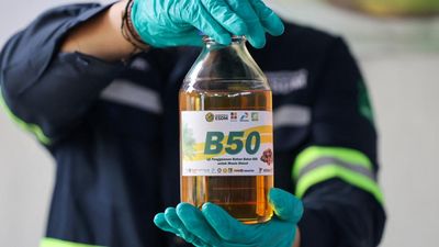 A laboratory technician poses for a picture as he holds a bottle of palm biodiesel 50% fuel during a B50 testing event, as Indonesia plans to raise the mandatory blending rate for palm-based biodiesel